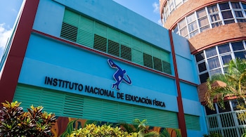 Edificio azul con detalles rojos, ventanas de persianas verdes, el logotipo de un atleta y el nombre "INSTITUTO NACIONAL DE EDUCACIÓN FÍSICA".