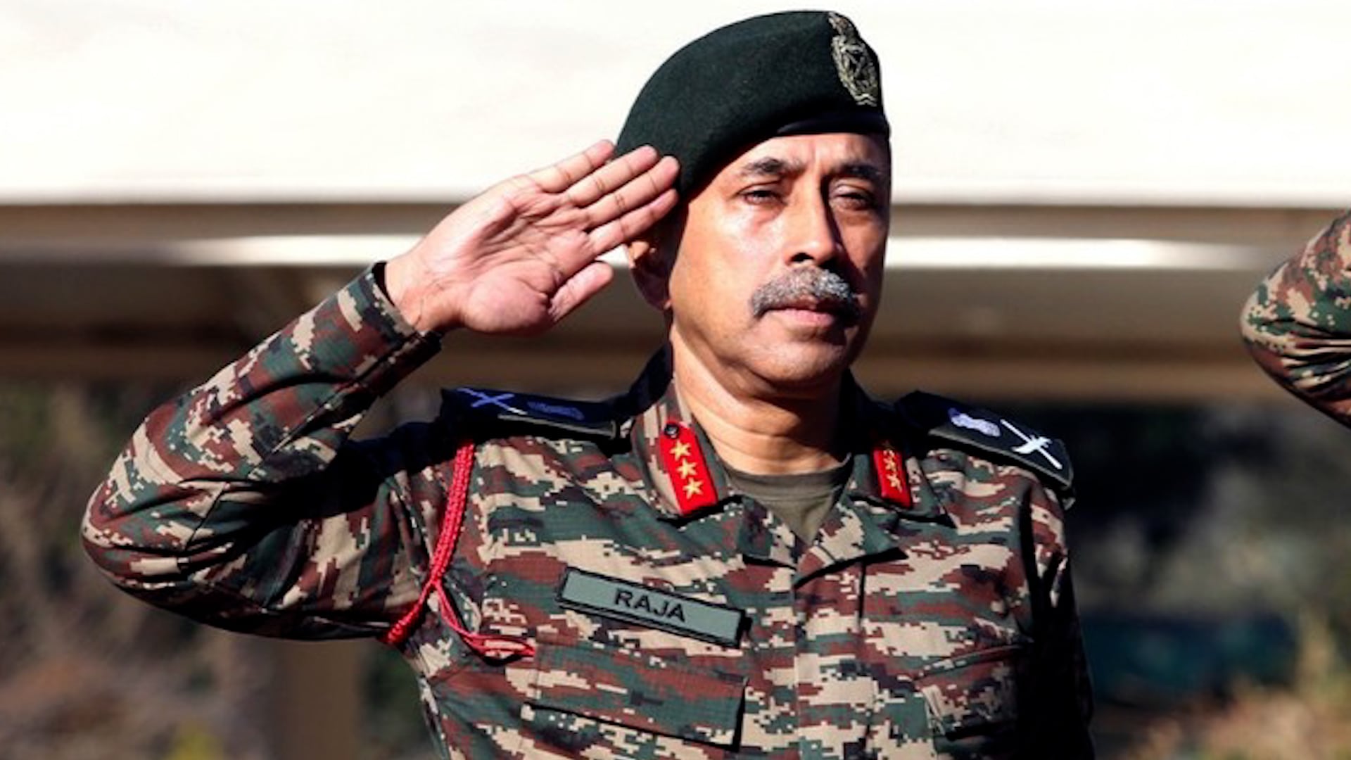 El oficial Raja Subramani, vestido con uniforme militar de camuflaje y boina, saluda mostrando respeto en un evento oficial.
