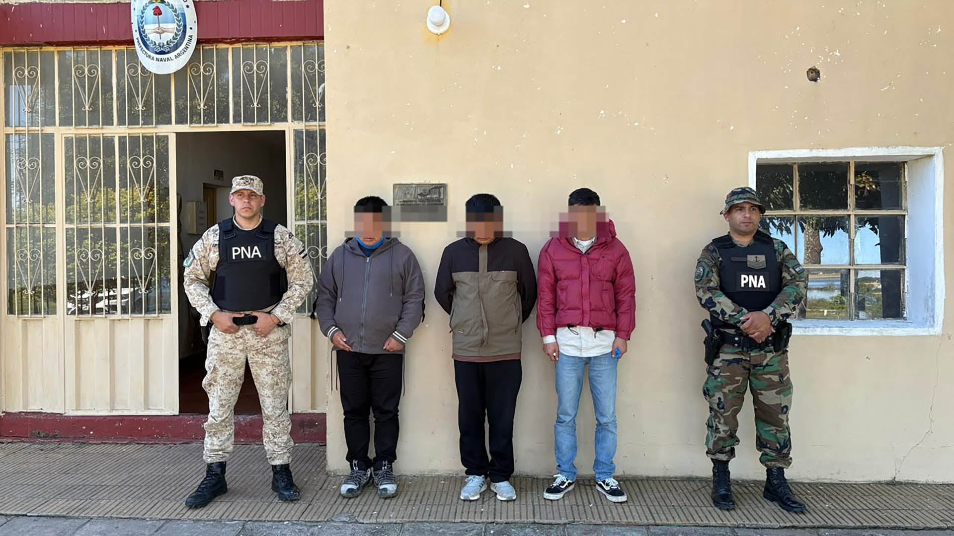 Agentes de la Prefectura Naval Argentina custodian a tres ciudadanos chinos