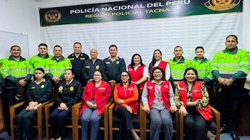 Grupo de catorce personas, uniformados y con chalecos rojos, posa frente a un cartel de la Policía Nacional del Perú, Región Policial Tacna