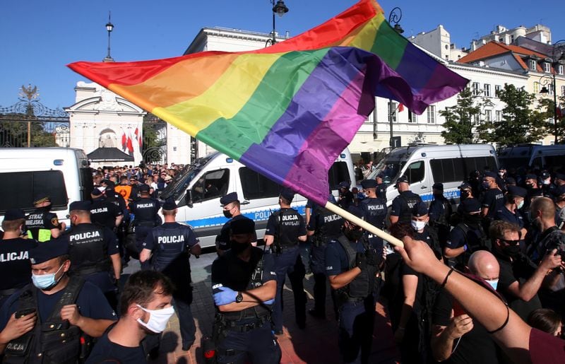 Un manifestante a favor de los derechos LGBTQ+ ondea una bandera arcoíris mientras nacionalistas polacos se reúnen para protestar contra lo que llaman