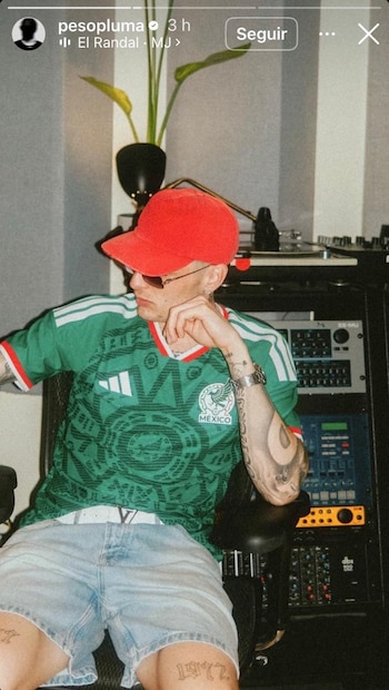 Hombre con gorra roja, gafas de sol y camiseta de fútbol de México sentado en una silla. Al fondo, equipo electrónico de audio y una planta