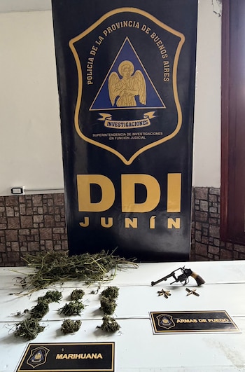 En una mesa blanca, se exhiben varias porciones de marihuana, un revólver y tres balas, con un banner azul de la DDI Junín de fondo