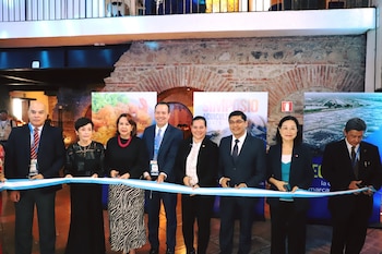 Nueve funcionarios en trajes de negocios cortan una cinta ceremonial. La escena sugiere un evento inaugural importante
