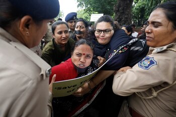 Police officers detain demonstrators during