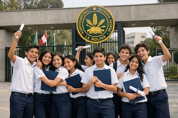 Grupo de adolescentes con uniforme escolar blanco y azul marino sostiene diplomas y carpetas azules frente a la Universidad Nacional Agraria La Molina.