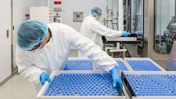 Técnicos de laboratorio cargan frascos