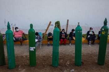 FOTO DE ARCHIVO-Personas sentadas cerca de tanques de oxígeno vacíos esperan para rellenarlos para pacientes que sufren de la enfermedad del coronavirus (COVID-19), fuera de un proveedor privado de oxígeno, en Lima, Perú. 25 de febrero de 2021. REUTERS/Sebastián Castañeda