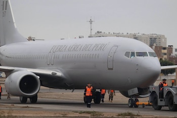 Avión Boeing 737-800NG gris de la Fuerza Aérea del Perú en pista de aterrizaje, con operarios en chalecos naranjas y un tractor de remolque