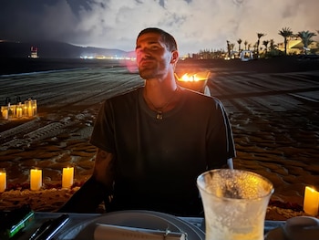 Rodrigo De Paul en una cena romántica en la playa: velas, fuego y una mirada perdida en el horizonte