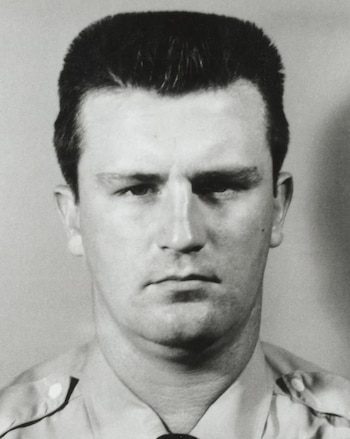 Retrato en blanco y negro de un hombre de cabello corto vestido con una camisa de uniforme