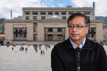Gustavo Petro, un hombre con gafas y chaqueta negra, frente a un micrófono, con el Palacio de Justicia y la Plaza de Bolívar llenos de gente al fondo.