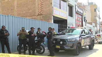 Varios efectivos policiales, una camioneta patrullera, una motocicleta y una cinta amarilla de seguridad frente a comercios en la calle