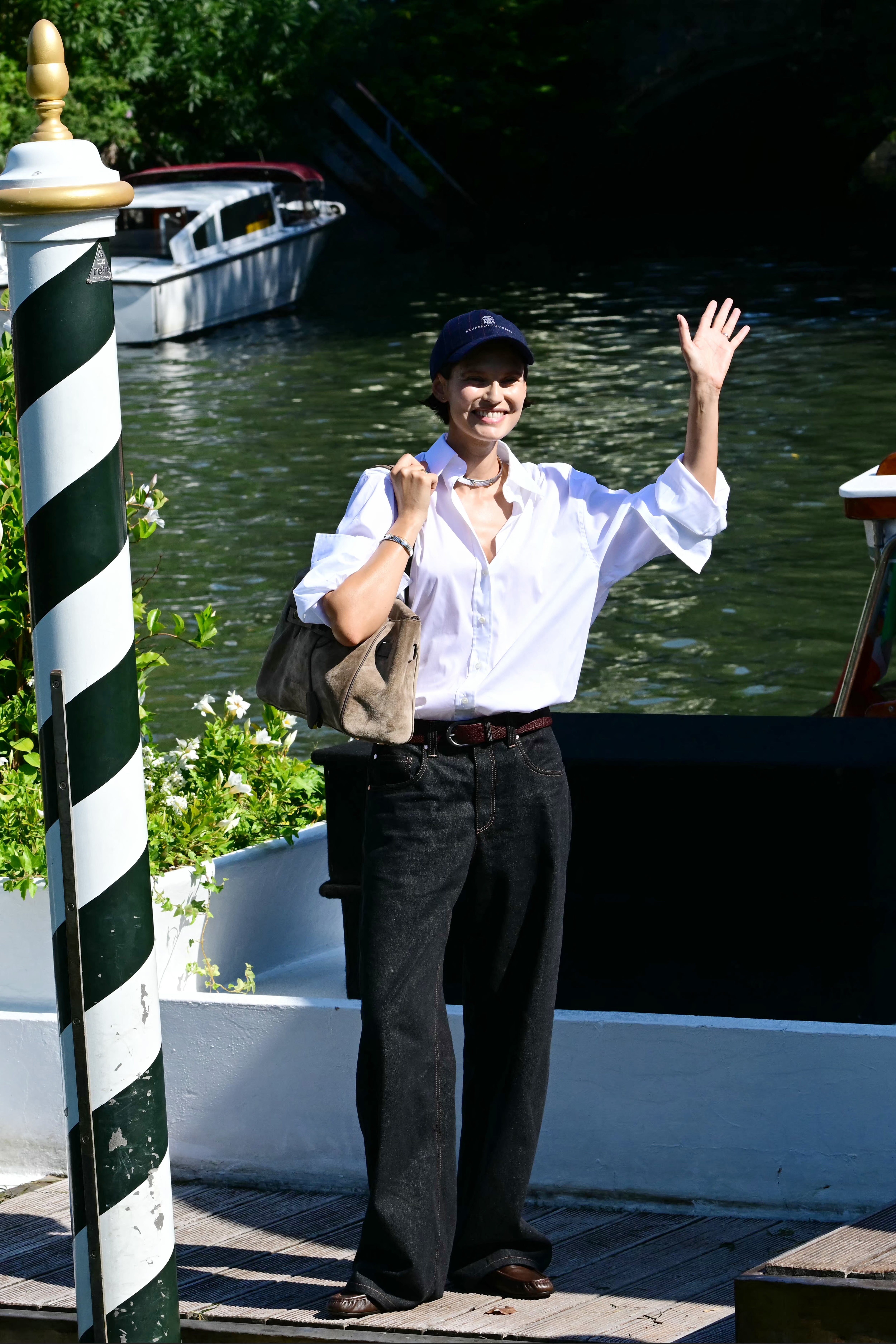 Bianca Balti con camisa blanca oversize, jeans oscuros y gorra azul marino junto a un canal (Photo by Stefano Rellandini / AFP)