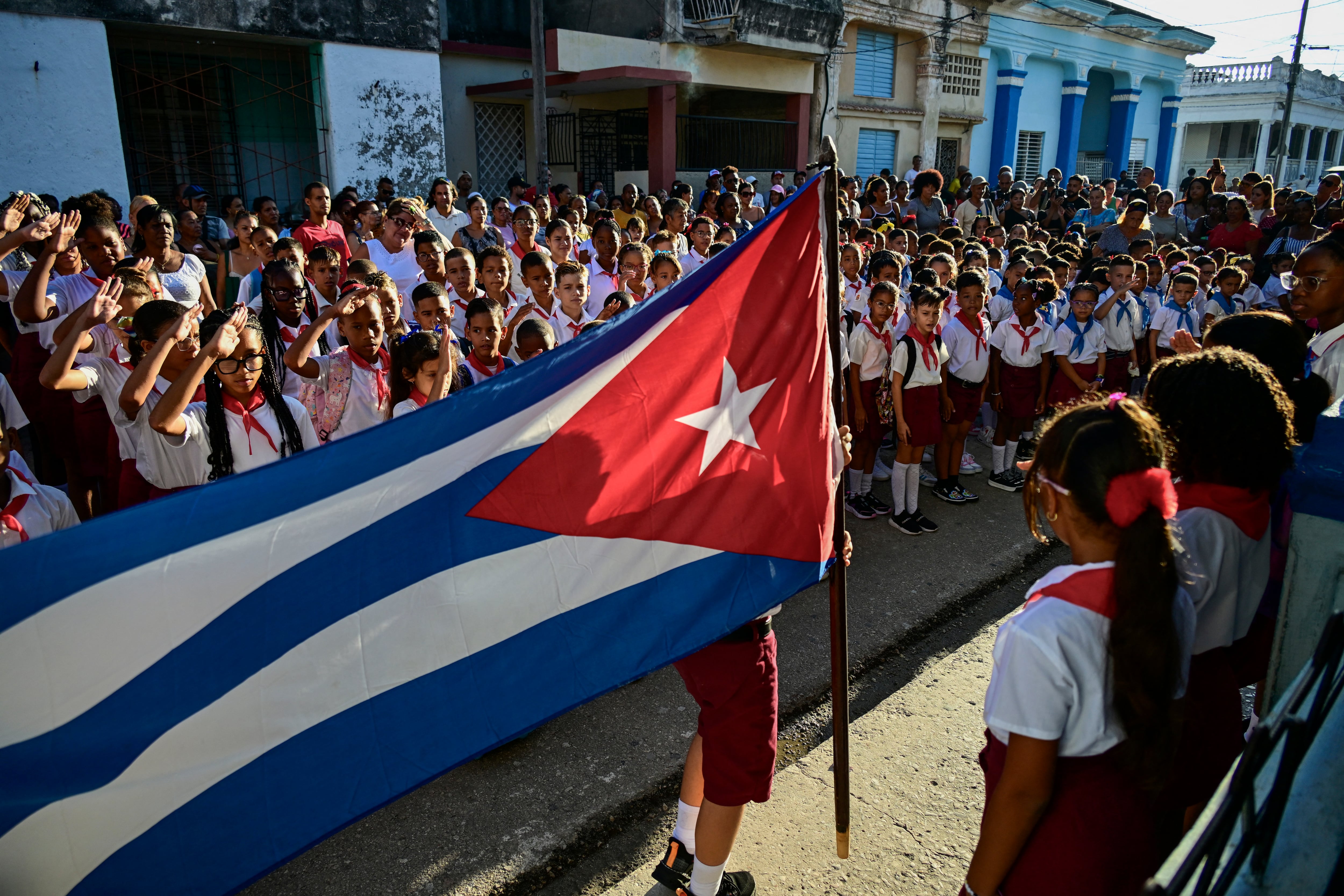Los estudiantes hacen el saludo escolar antes de entrar a sus aulas en el primer día del año académico 2026-2027 en La Habana, el 1 de septiembre de 2026. En medio de la escasez de uniformes y de maestros, así como de prolongados cortes de electricidad, 1,4 millones de estudiantes iniciaron un nuevo curso escolar el 1 de septiembre en Cuba, donde la crisis económica obliga a las familias a asumir los crecientes costos de la educación de sus hijos. (Infobae Cuba/ YAMIL LAGE / AFP)