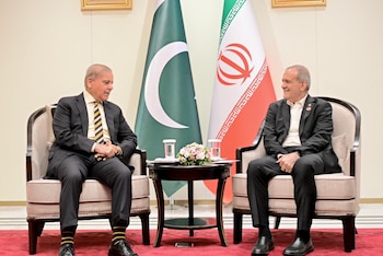 Shehbaz Sharif y Masud Pezeshkian sentados en sillones frente a las banderas de Pakistán e Irán