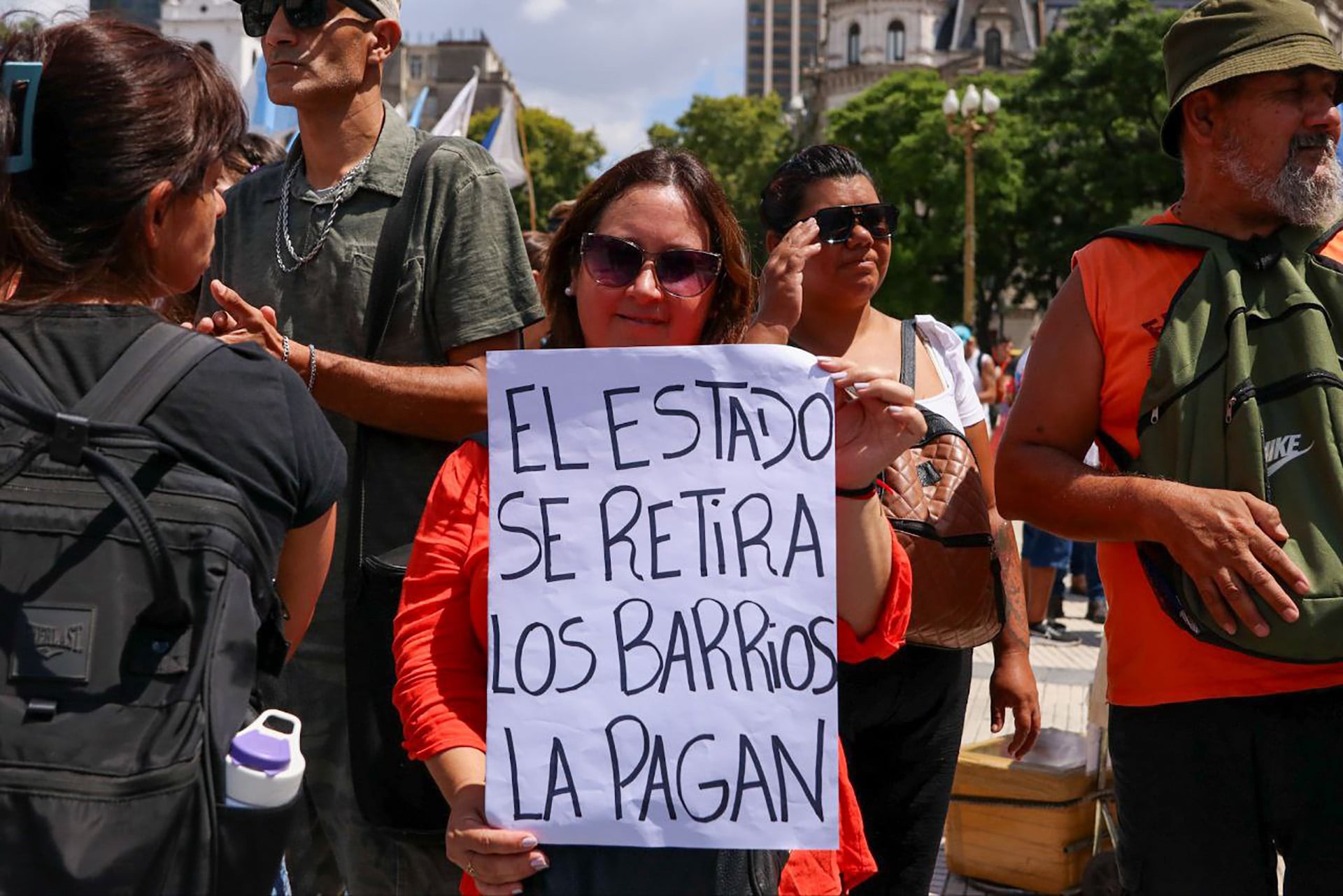 Una mujer sostiene un cartel con el mensaje 'El Estado se retira, los barrios la pagan' durante una manifestación convocada por la UTEP