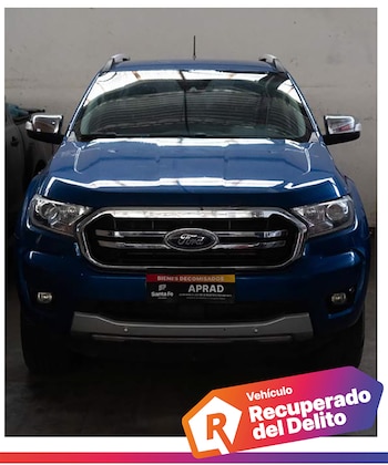 Parte frontal de una camioneta azul con una placa con el texto de bienes decomisados de APRAD y una etiqueta gráfica al pie