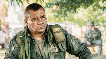 Ilustración digital estilo acuarela de un hombre de mediana edad con uniforme militar verde y expresión seria, mirando a la derecha con un fondo natural borroso.
