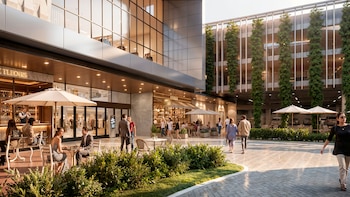 Moderno centro comercial Unicenter con tiendas, restaurantes al aire libre y personas. Edificios de vidrio y un aparcamiento vertical con vegetación