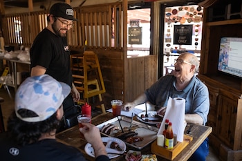 Alfredo Tapia saluda a Scott Urice (derecha) y a Daniel Valles a la hora del almuerzo en Roegels Barbecue Co (Antranik Tavitian/For The Washington Post)