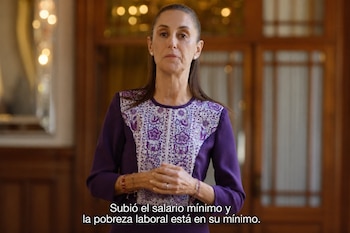 Claudia Sheinbaum con un vestido morado y bordados blancos, con las manos entrelazadas y un subtítulo en la parte inferior.
