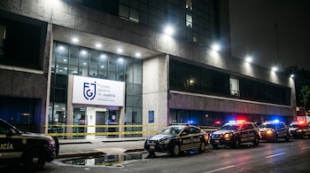 Fachada nocturna de la Fiscalía General de Justicia de la Ciudad de México, con su logo, cinta amarilla de acordonamiento y varias patrullas policiales.
