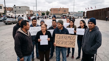 Personas al aire libre sostienen pancartas con los textos Queremos respuestas, Derechos Humanos y Justicia cerca de un muro fronterizo.