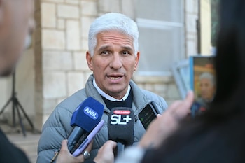 Claudio Poggi habla rodeado de micrófonos y teléfonos móviles sostenidos por periodistas frente a una pared de piedra