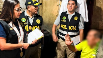 Una fiscal y dos policías con chalecos oficiales interrogan a un hombre sentado con el rostro difuminado en una habitación