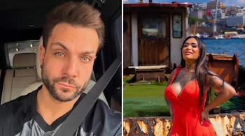 Primer plano de hombre barbudo con camisa oscura y cinturón de seguridad en un coche; mujer de cabello oscuro con vestido rojo y tatuajes frente al mar.