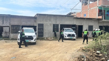 Policías peruanos con chalecos verdes se encuentran frente a dos camionetas policiales blancas y edificios de concreto en un área rural o semi-urbana