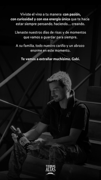 Hombre sentado en una escalera observando una botella de vino que sostiene en sus manos, con texto superpuesto en blanco y negro
