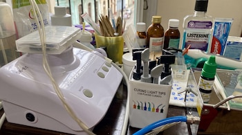 Un dispositivo de odontología, un frasco de enjuague bucal, un tubo de crema dental e instrumentos de cura sobre un mostrador.