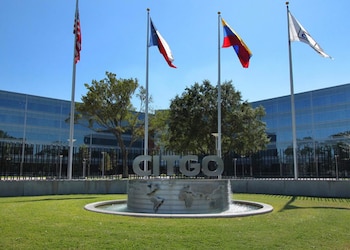 Edificio de Citgo con su letrero y fuente. Ondearan cuatro banderas: Estados Unidos, Texas, Venezuela y una bandera blanca con logo corporativo