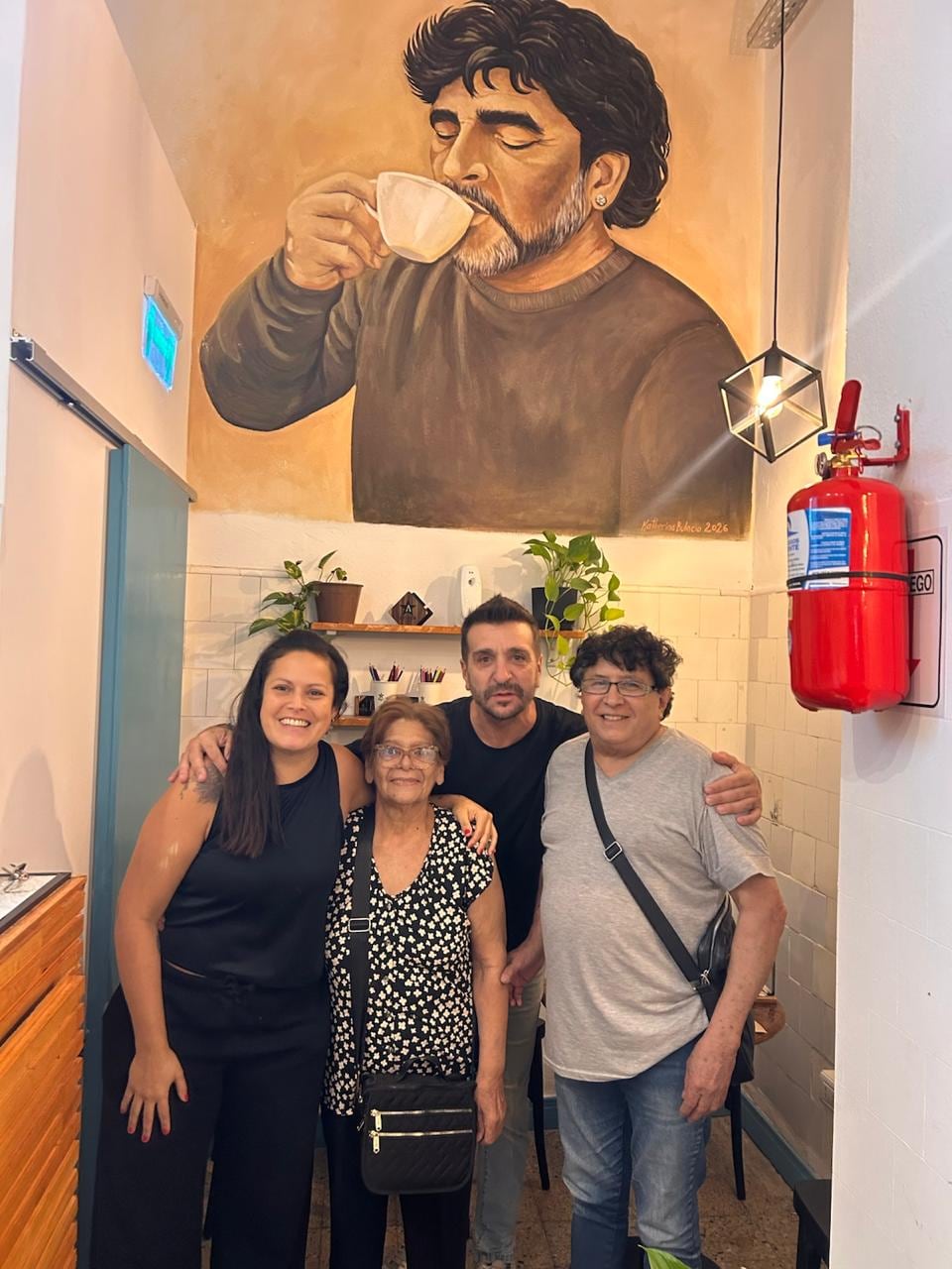 Diego Arvilly y Laura Villanueva posan junto a Ana Maradona. De fondo, el mural del Diez (@astroscafe_)