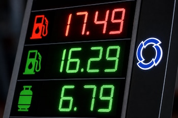 Pantalla digital con cifras LED rojas y verdes, iconos de surtidores de combustible y de un balón de gas, junto a un logotipo circular azul.