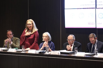 Vista lateral de varias personas sentadas en butacas rojas, aplaudiendo. En primer plano, dos mujeres con cofias de enfermera; una viste de blanco, otra de verde