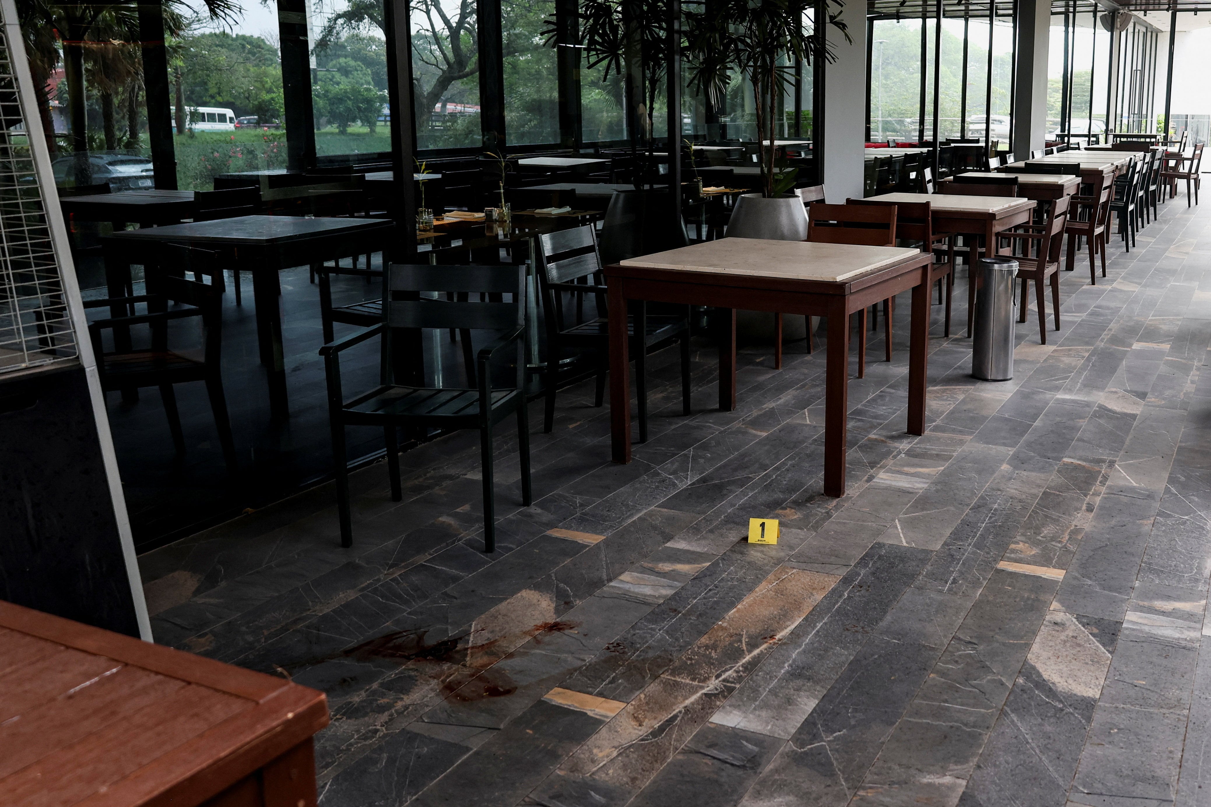 An evidence marker sits next to blood stains at a hotel restaurant where political commentator Nadia Beller was shot by a man dressed as a delivery rider, in Santa Cruz, Bolivia, August 18, 2026. REUTERS/Ipa Ibanez