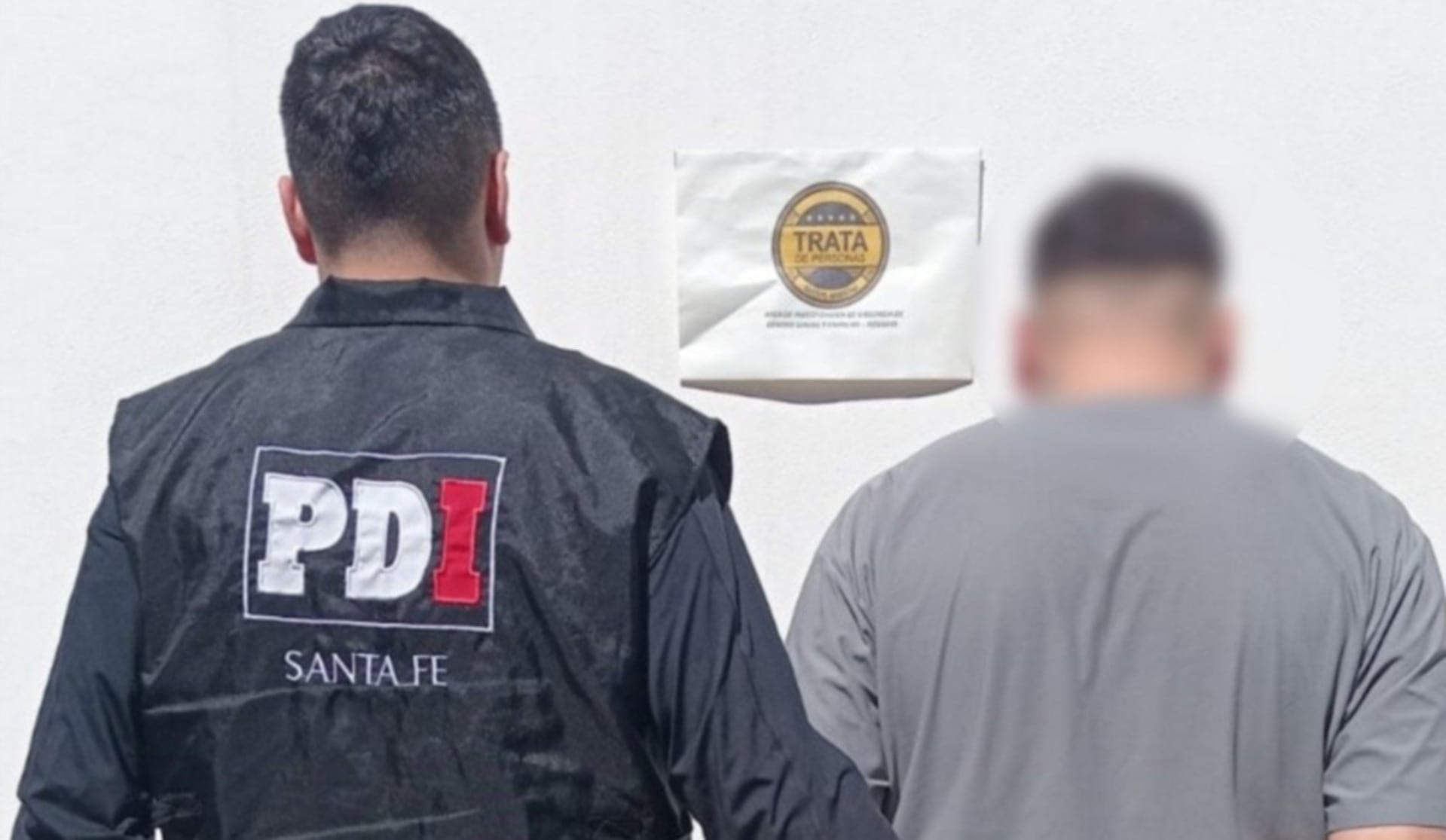Un agente de la PDI de Santa Fe escolta al hombre detenido en Rosario, acusado de abuso sexual contra la hija adolescente de su ex pareja. (Rosario3)