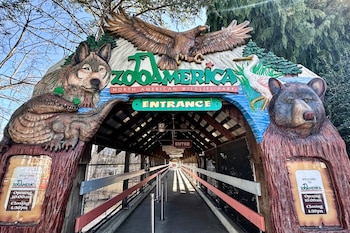 La entrada principal del ZooAmerica North American Wildlife Park, con una estructura de madera adornada con esculturas de un lobo, un águila y un oso