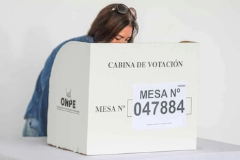 Mujer con cabello oscuro y gafas de sol sobre la cabeza vota en cabina electoral blanca con logo ONPE y número de mesa 047884