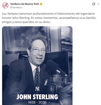 Póster en blanco y negro de John Sterling, un hombre sonriente con gafas, traje y corbata, sentado ante un micrófono. Abajo, el logo de los Yankees y las fechas 1938-2026