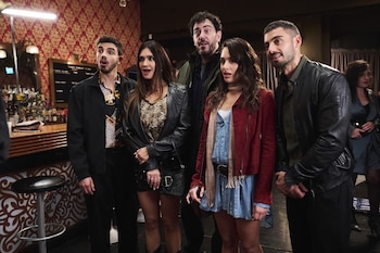 Un grupo de cinco personas de pie dentro de un bar mira hacia el frente con expresiones atentas