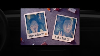 Pantalla digital de un automóvil que exhibe dos fotografías instantáneas con mensajes de Halloween y dulces a su alrededor