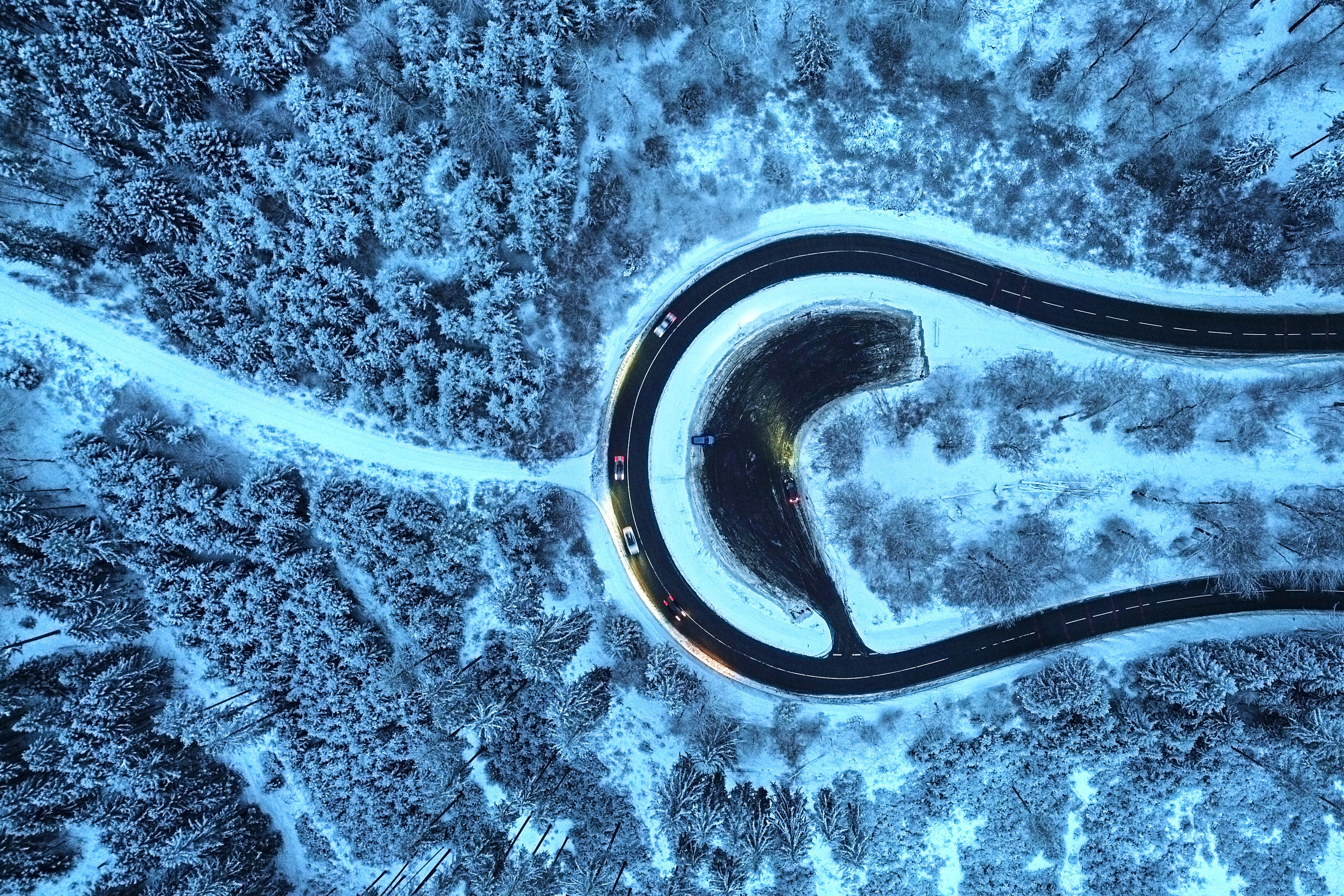 Autos circulan por una curva en un bosque nevado de la región de Taunus, cerca de Frankfurt, Alemania, el martes 6 de enero de 2026. (Foto AP/Michael Probst)