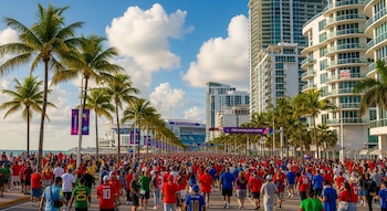 Multitud de personas camina en Miami, rodeada de palmeras, rascacielos modernos y un estadio con publicidad de la Copa Mundial FIFA 2026.