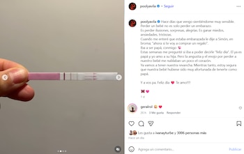 Primer plano de una mano sujetando un test de embarazo con una línea horizontal rosada visible sobre un fondo gris claro