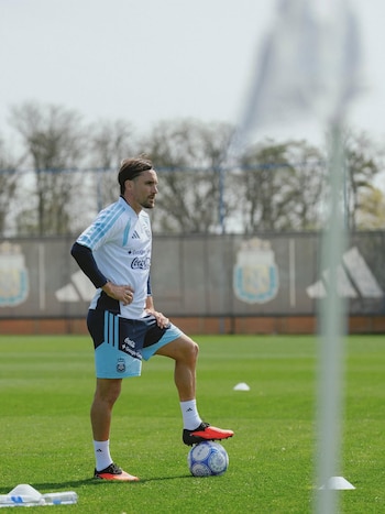 Nicolás Tagliafico de pie en una cancha de césped con uniforme de la selección argentina y un pie sobre una pelota de fútbol