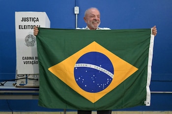 Brazil's President and Workers' Party (PT) re-election candidate Luiz Inacio Lula da Silva holds a Brazilian flag at a polling station during the presidential runoff election in Sao Bernardo do Campo, Sao Paulo state, Brazil, on October 25, 2026. Lula da Silva faces right-wing senator Flavio Bolsonaro in a runoff that will determine whether Brazil remains one of the few leftist nations in the region or joins a regional swing to the right championed by US President Donald Trump, Bolsonaro's ally. (Photo by NELSON ALMEIDA / AFP)